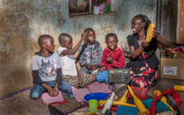 A mother and four children play together while listening on the radio to Remote Play Lab learning content in Uganda